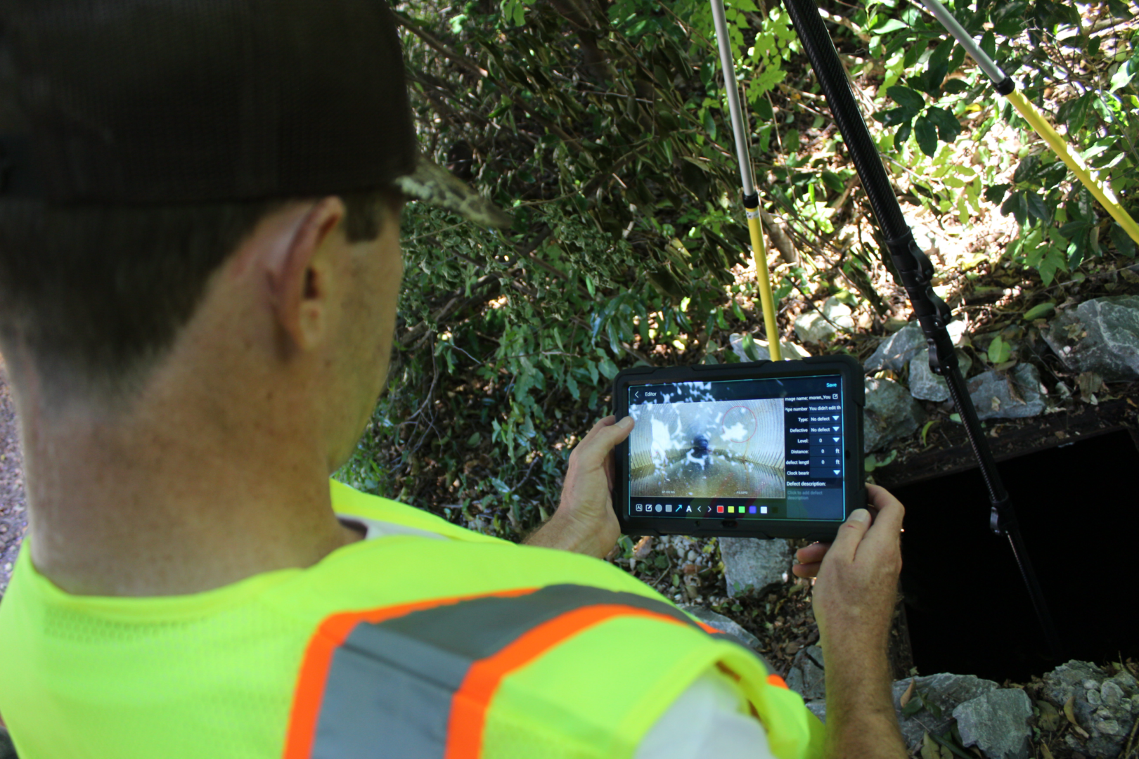 A man in safety vest looking at an ipad.